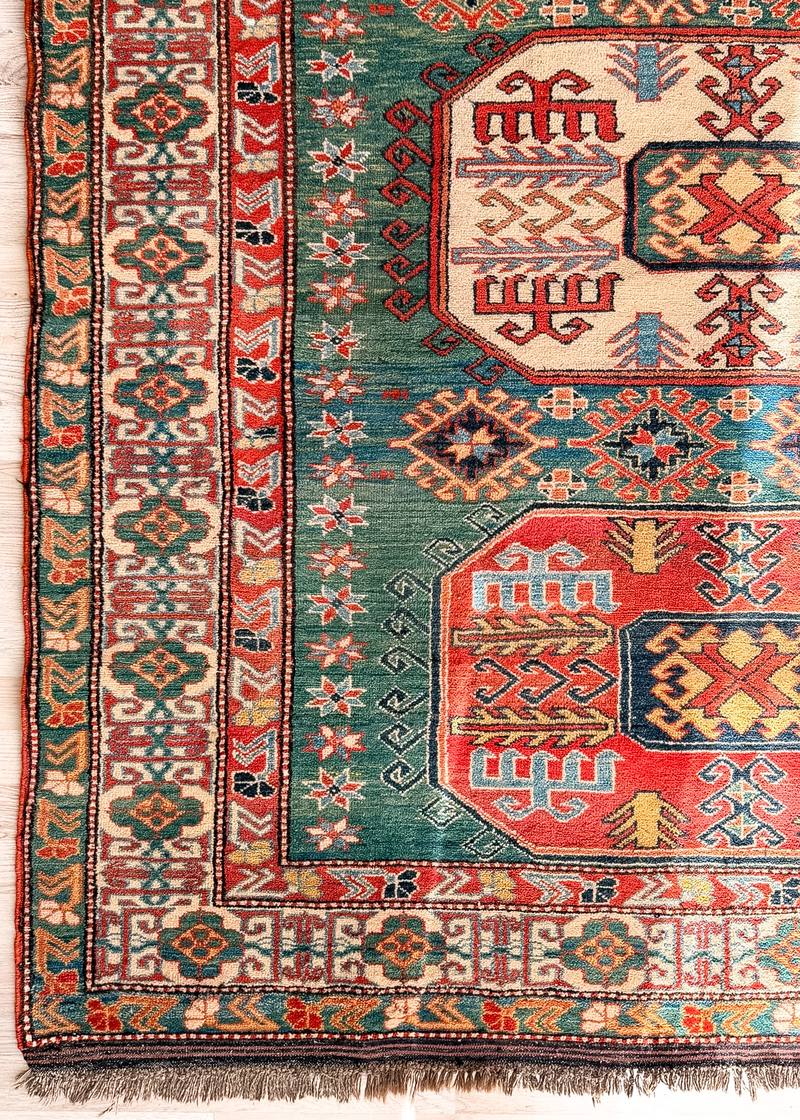 Corner of Asya, a vintage Kazak-design rug with a green field and red and ivory medallions
